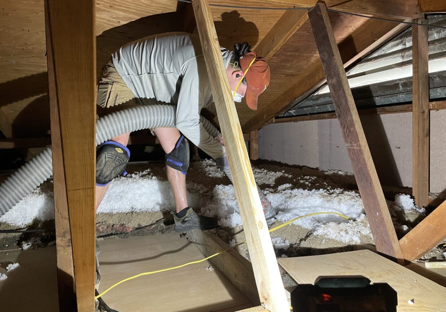 A man working in the attic of an unfinished house.